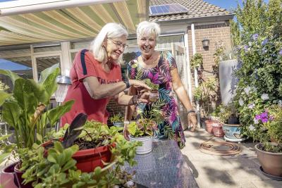 Thuishulp en client staan buiten bij de plantjes