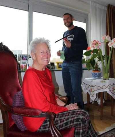 Tony zeemt de ramen en mevrouw Greetje kijkt vanuit haar stoel vrolijk toe.